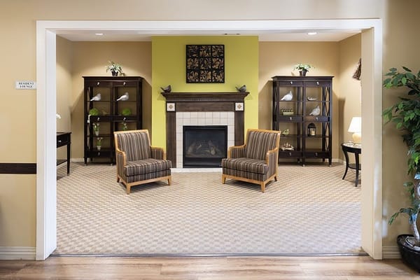 Resident lounge featuring two striped chairs and a fireplace