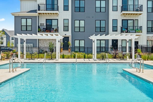 Outdoor swimming pool with loungers and pergolas in front of the residential building