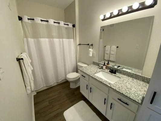 Modern bathroom with granite countertops and white shower curtain