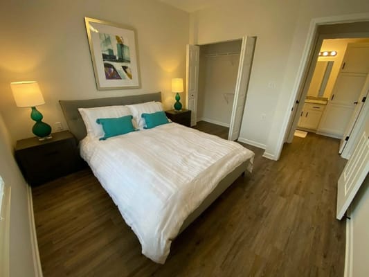 A well-furnished bedroom with a queen-sized bed, nightstands, and lamps.