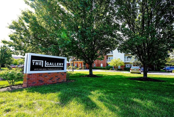 Sign for The Gallery Apartments amidst landscaped greenery