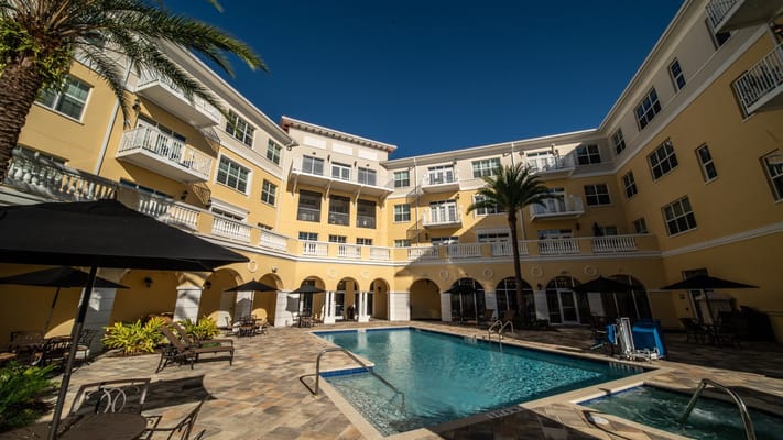 Outdoor pool area with lounge chairs and palm trees