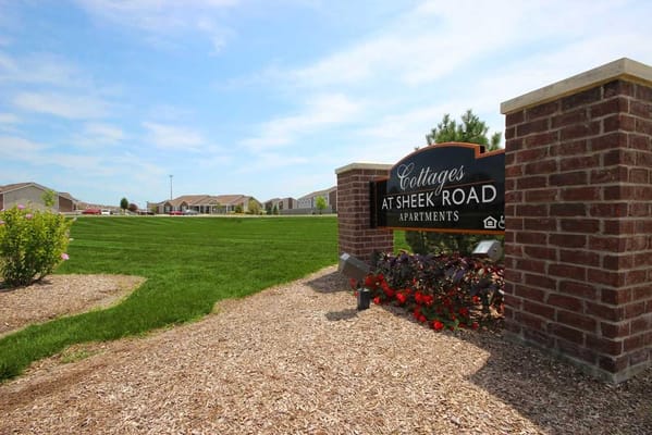 Sign for Cottages at Sheek Road Apartments with green lawn