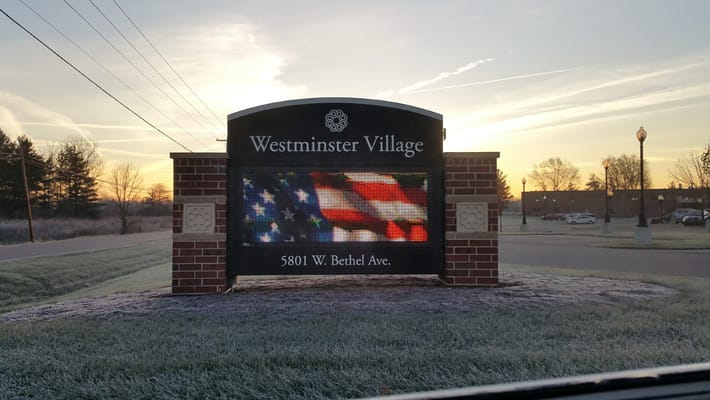 Signage for Westminster Village facility with an American flag display