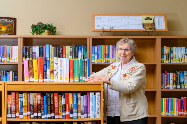 A resident poses in a library with shelves of books