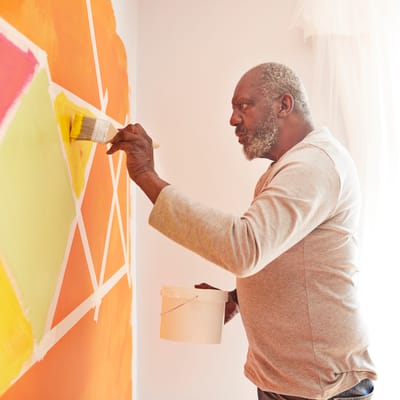 A resident painting a colorful wall in a facility.