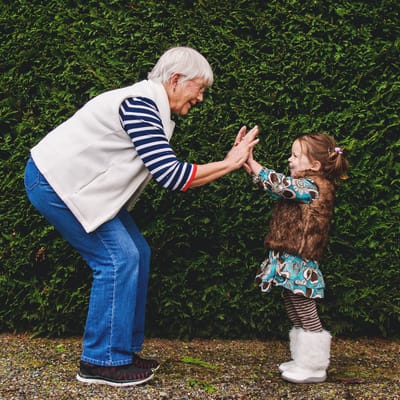 An elderly woman playing with a young girl outdoors