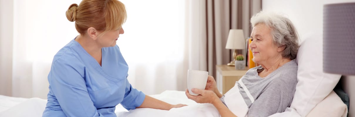 Caregiver assisting an elderly woman in bed