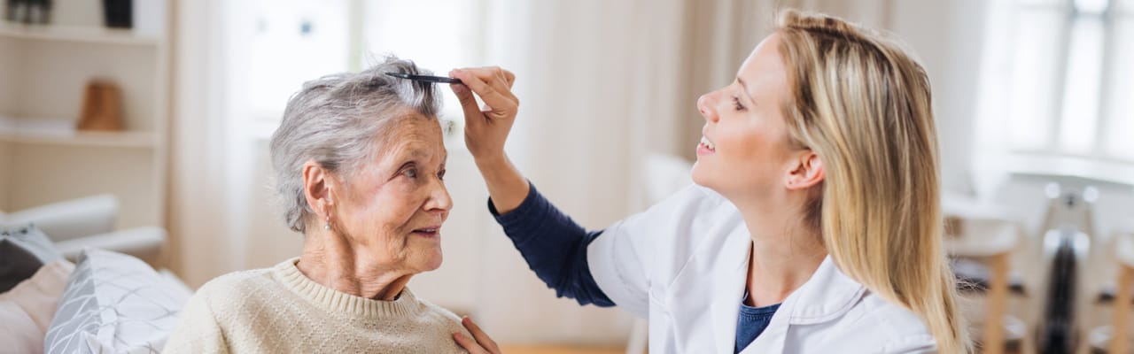 Caregiver styling elderly woman's hair in a bright room