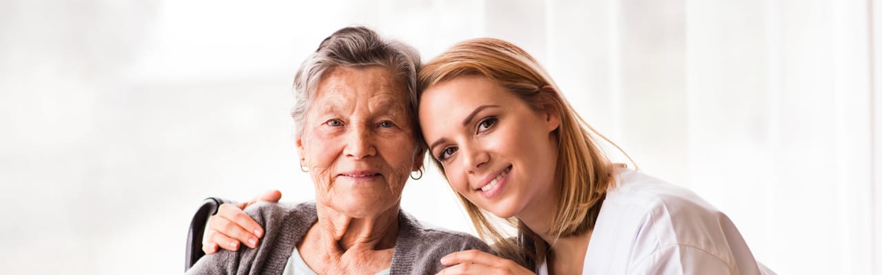 A caregiver and a senior resident smiling together