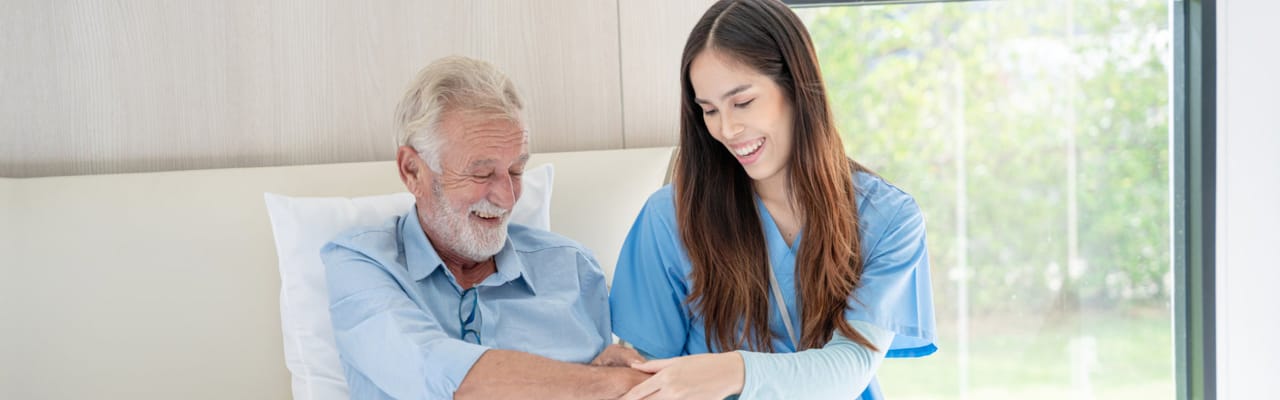 A caregiver smiling with an elderly resident in a room