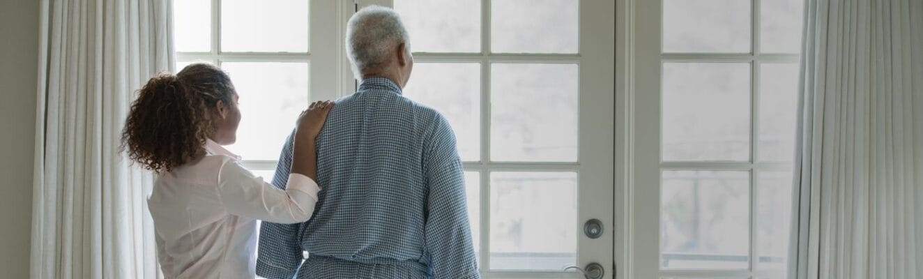 A caregiver assisting a senior resident by a window