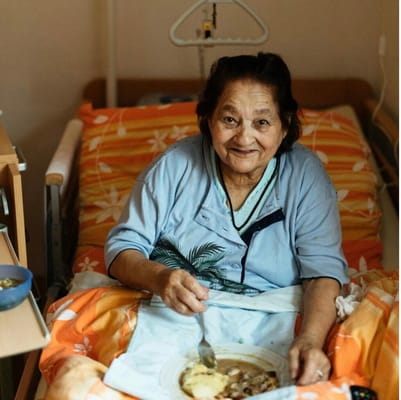Elderly woman enjoying a meal in her room