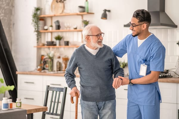 A caregiver assisting a senior resident in a bright kitchen