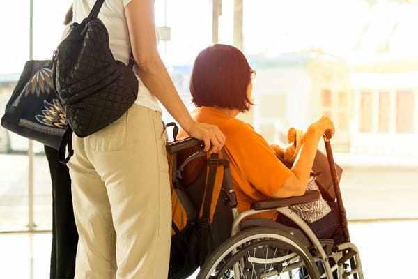 Woman assisting a resident in a wheelchair indoors