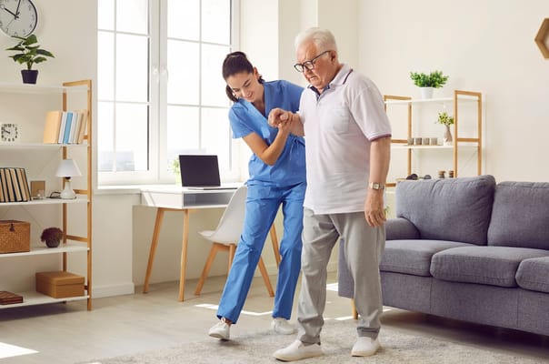 Caregiver assisting a senior man in a bright room