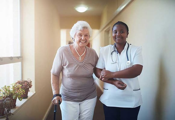 Nurse assisting a resident in a corridor