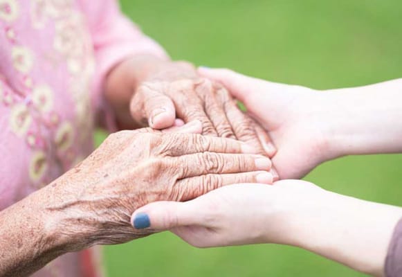 Hands of a resident and caregiver in a caring moment