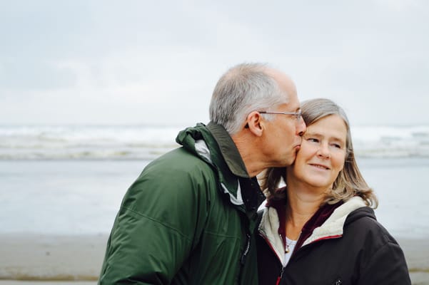 An older couple sharing a kiss on a beach