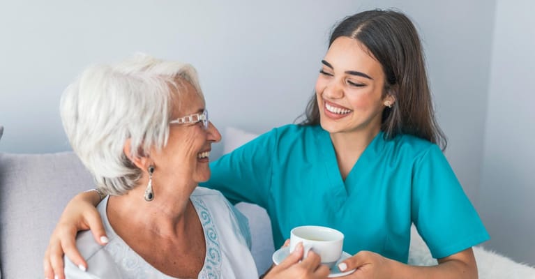 A caregiver enjoys a tea with a resident