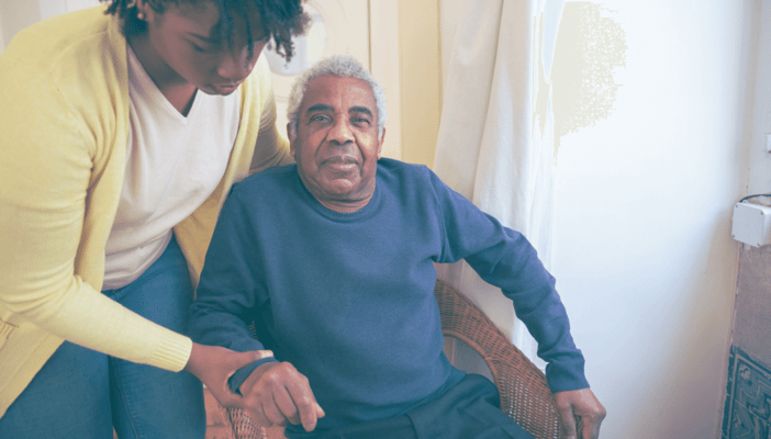 A caregiver assisting an elderly man in a chair