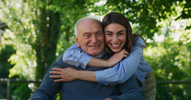 A caregiver and resident smiling together outdoors