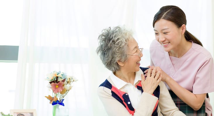 A caregiver smiling with a resident in a well-lit room