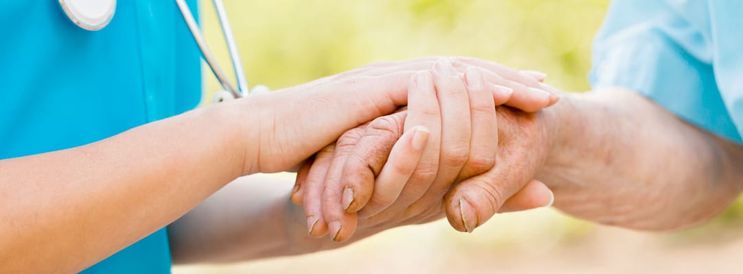 Close-up of a caregiver holding a senior's hand