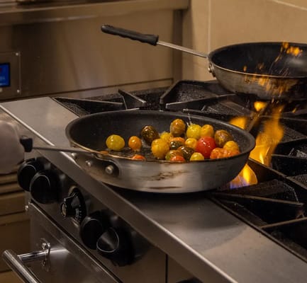 Chef preparing sautéed tomatoes in a kitchen