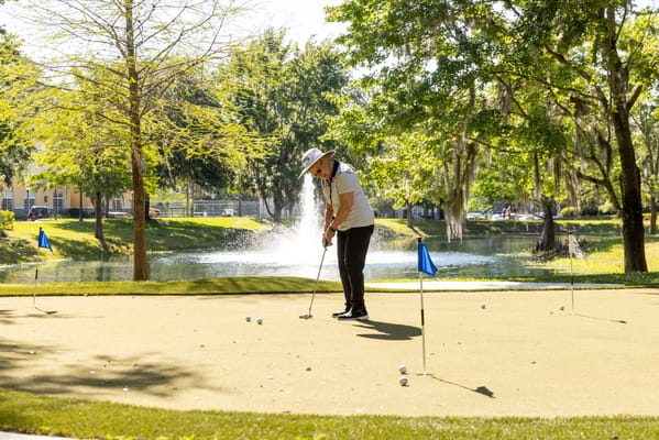Resident practicing golf putting in a sunny outdoor space