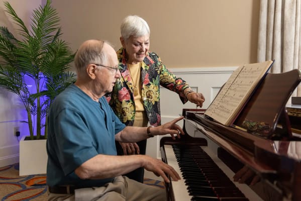 Residents enjoying music together at a piano