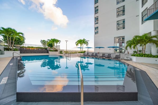 Outdoor pool area with lounge chairs and palm trees