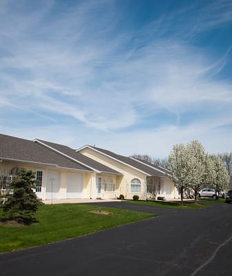 Exterior view of a senior living facility with trees and a driveway