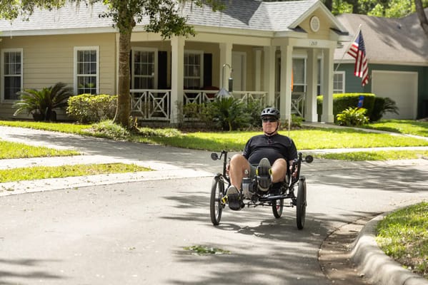 Resident riding a recumbent trike on a sunny street