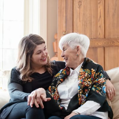 Two women smiling and enjoying each other's company in a cozy interior.