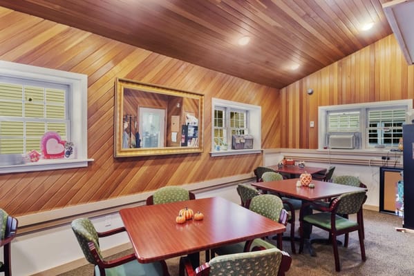 Brightly lit common area with wooden walls and tables