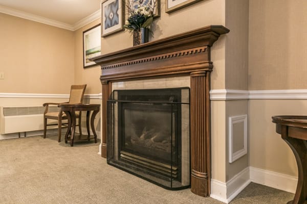 A warm fireplace surrounded by wooden furniture and artwork