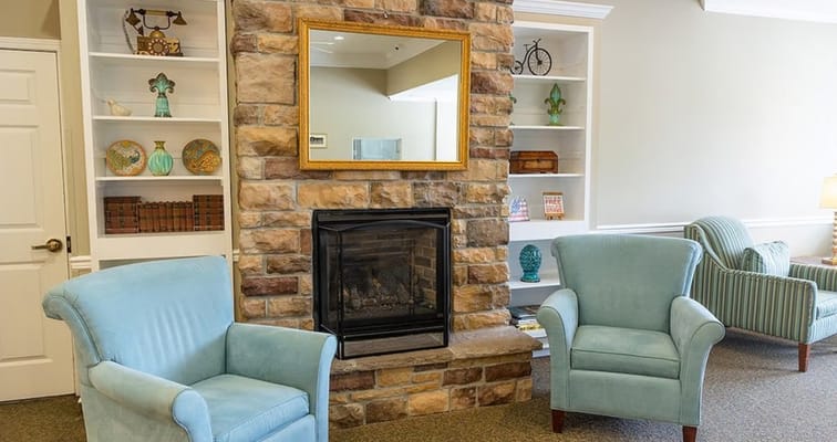 Interior view of a cozy common area with chairs and fireplace