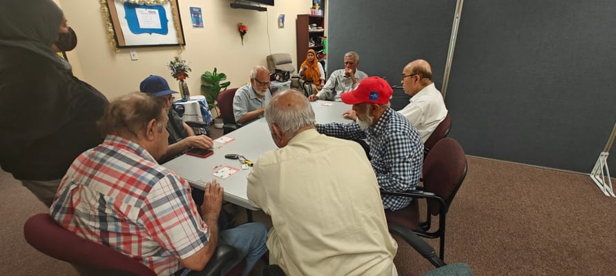 Seniors engaging in a card game at a table in a community room.