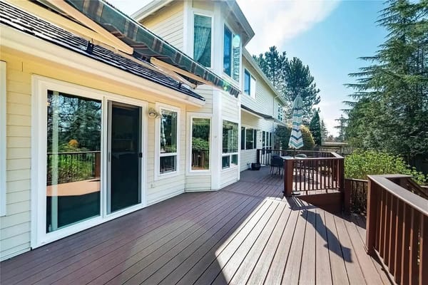 Spacious outdoor deck with furniture and trees in the background.