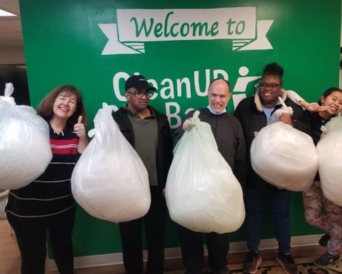 Group of five people holding large bags during a cleanup event.