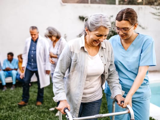 Caregiver assisting a resident with mobility outdoors