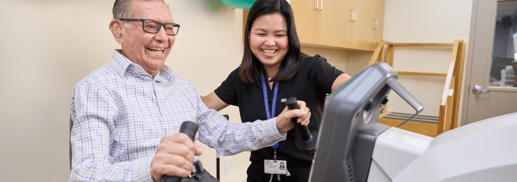 Resident using exercise equipment with staff assistance