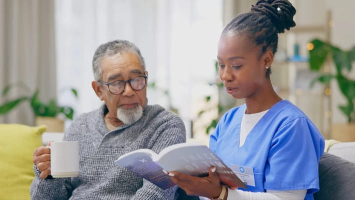 Resident enjoying a book with a caregiver