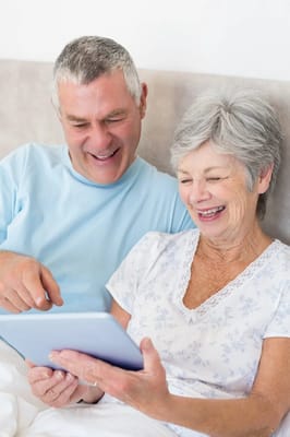 An older couple enjoying a tablet together in bed