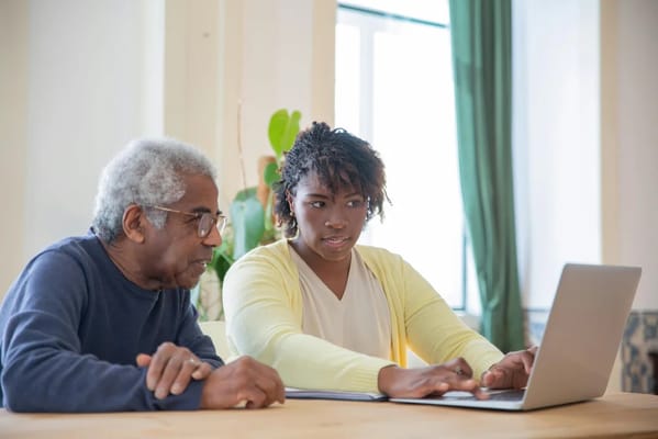Senior resident and staff looking at a laptop together