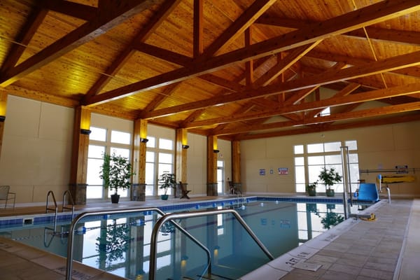 Indoor pool area with wooden beams and windows