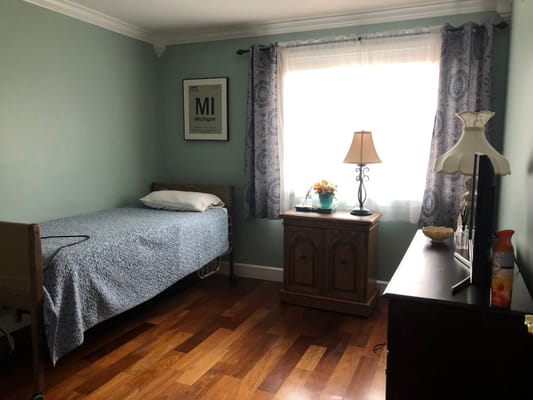 A private resident room with a bed and lamp