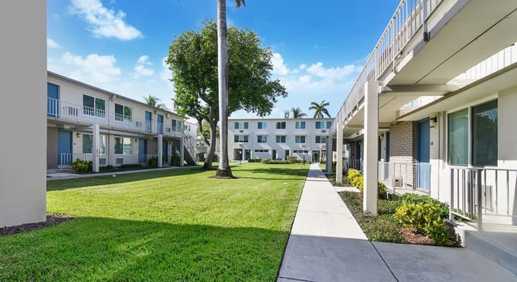 Bright courtyard with palm trees and adjacent buildings at Gateway Terrace Senior Apartments