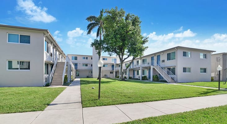 View of the Gateway Terrace Senior Apartments complex with green lawns and palm trees.